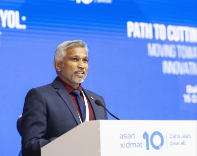Mohamed Shareef speaking at a lectern marked asan xidmət 10, in front of a blue screen reading Path to Cutting-Edge Governance